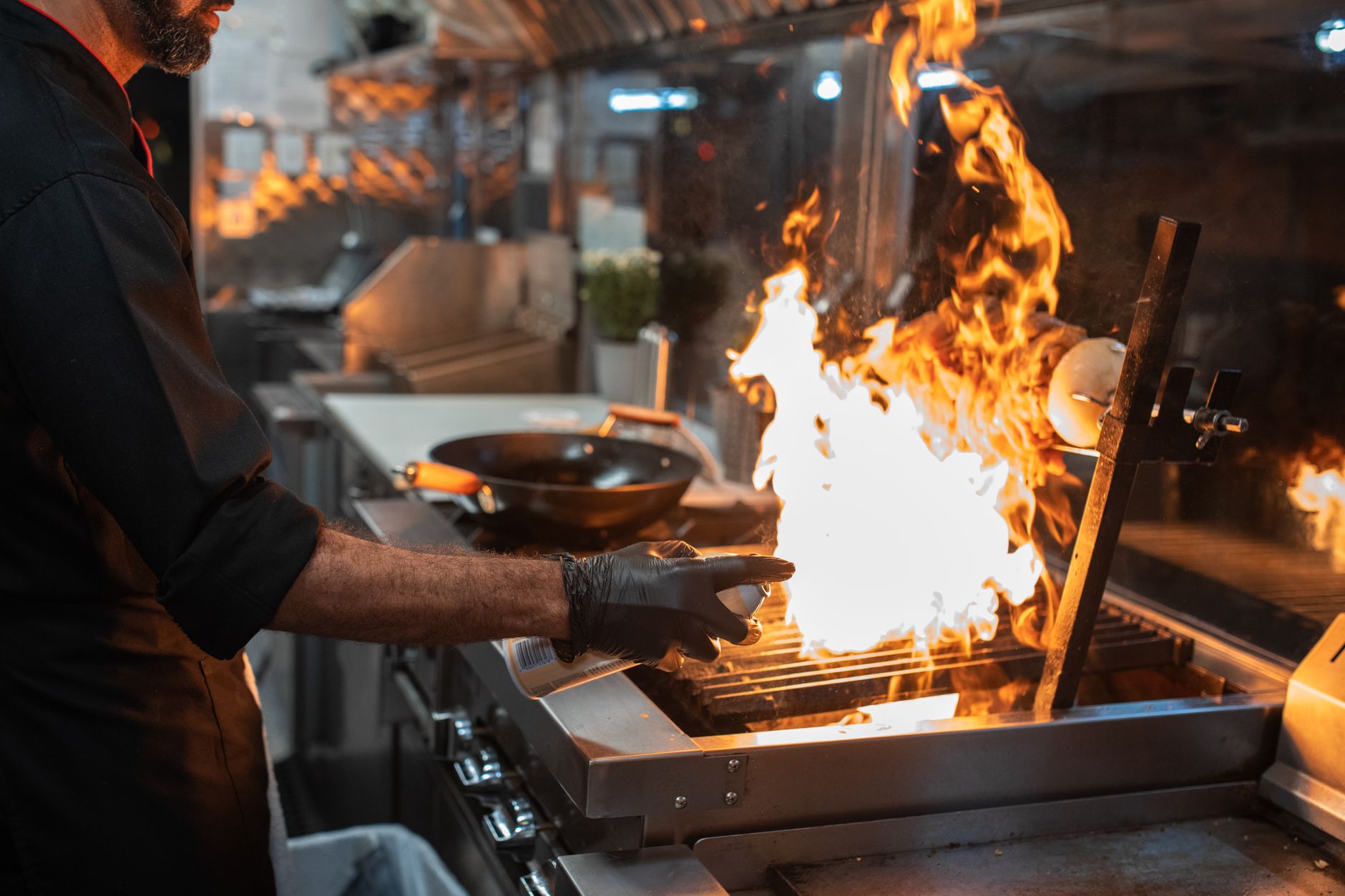 Professional grill restaurant interior with chef cooking at open flame kitchen, modern lighting and stainless steel equipment