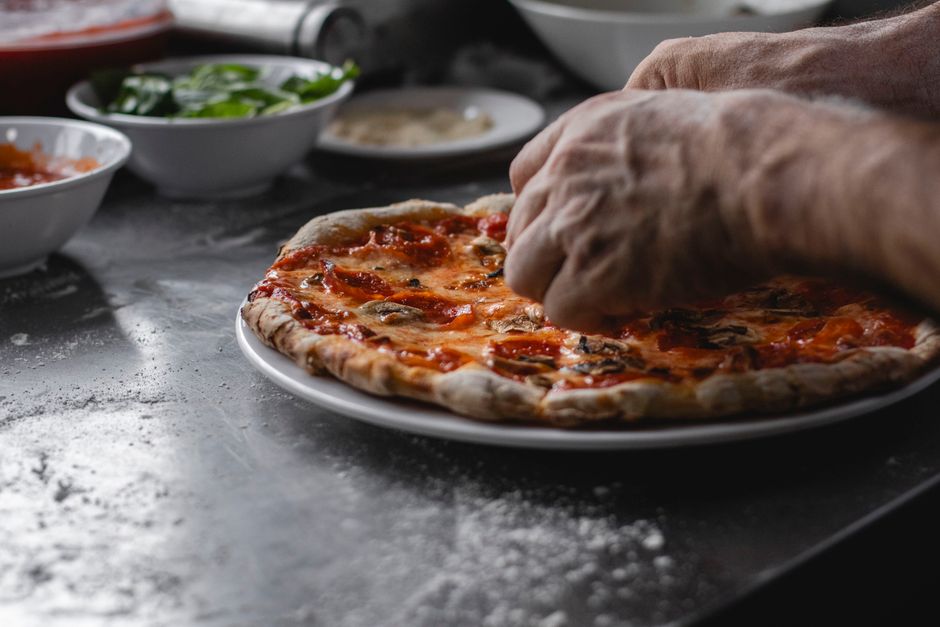Pizza kitchen with chef preparing fresh pizza dough, artisan style cooking with traditional techniques